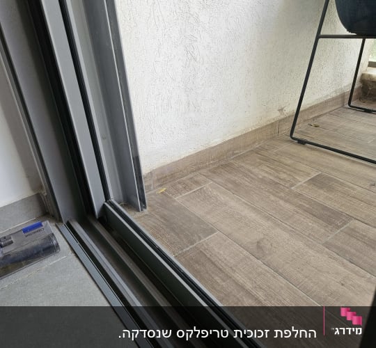 דלת זכוכית עם מסגרת מתכת על רצפת עץ